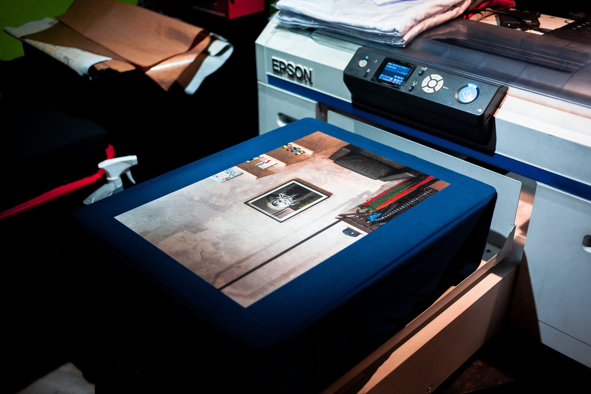 A direct-to-film transfer being applied to a dark T-shirt with a heat press